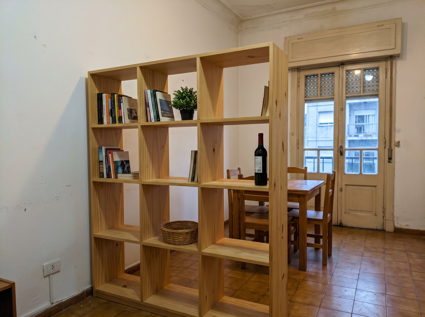 Biblioteca de pino macizo abierta de ambos lados que separa el living del comedor en un apartamento de Montevideo.