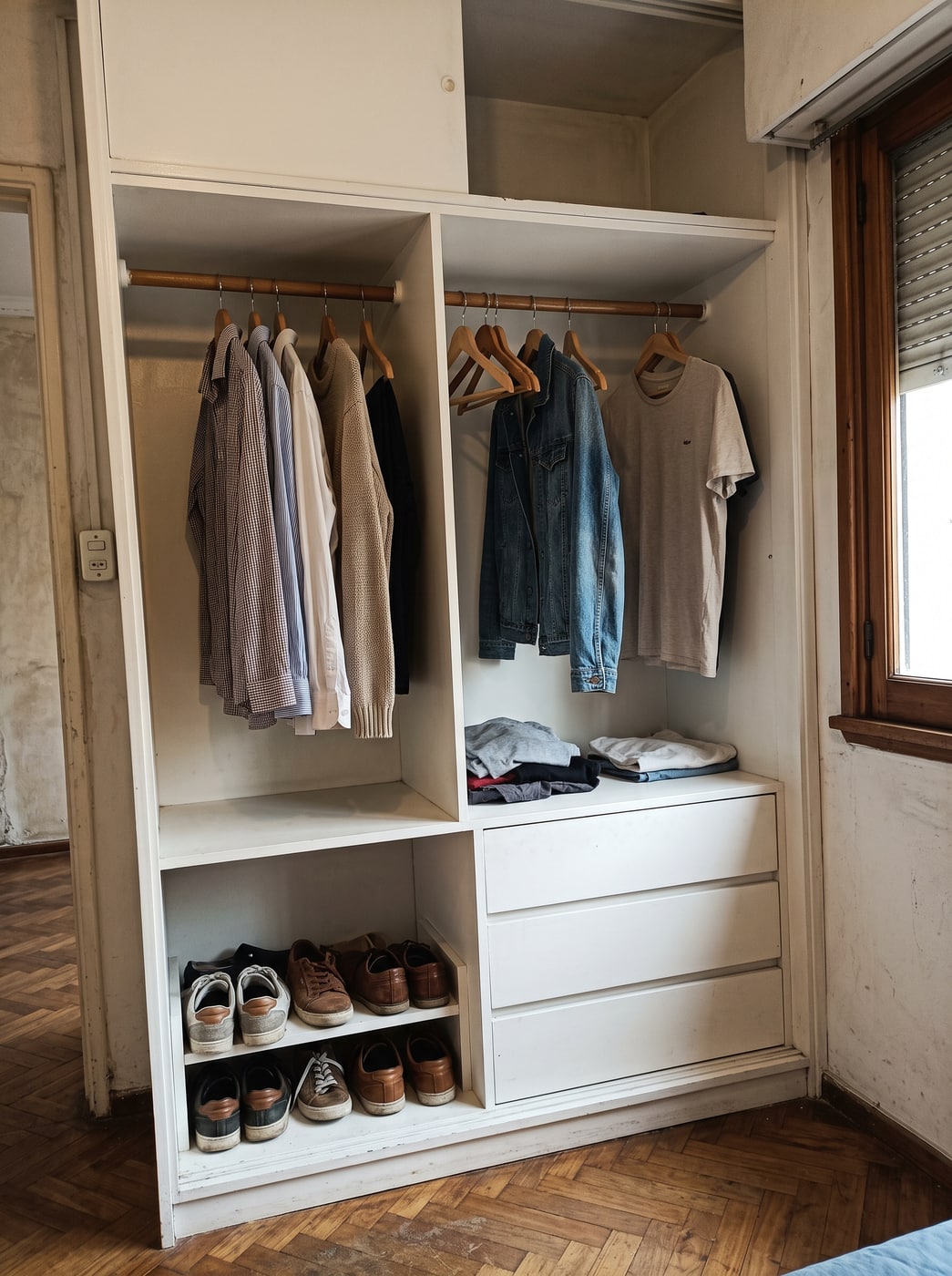 Interior de placard laqueado blanco con dos barrales a distinta altura, cajonera central, zapatero y ropa colgada.